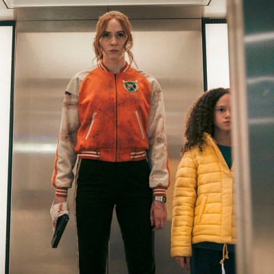 Karen Gillan as Sam stands in an elevator with a gun taped to her hand in Gunpowder Milkshake