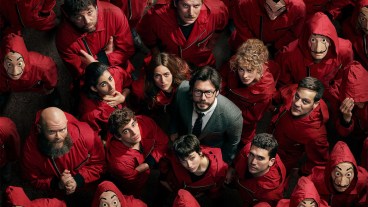 The cast of Money Heist look up in a crowd of people in red