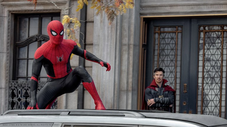 Spider-Man crouches on top of a car while Dr. Strange looks on with his arms crossed