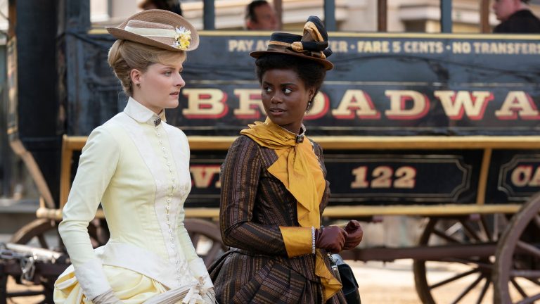 Louisa Jacobson as Marian Brook and Denée Benton as Peggy Scott walk in front of a stage coach in The Gilded Age