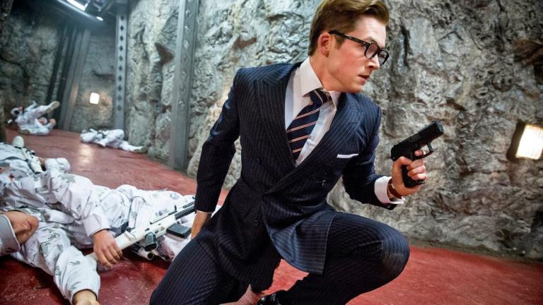 Taron Egerton crouches with a gun in his hand in Kingsman