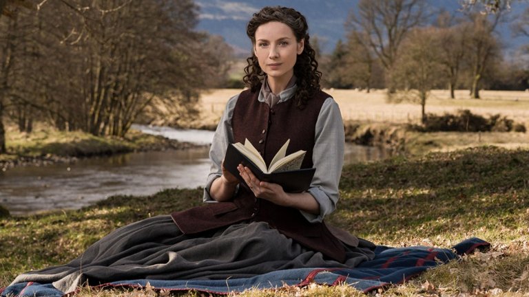 Claire sits outside reading a book in Outlander Season 6