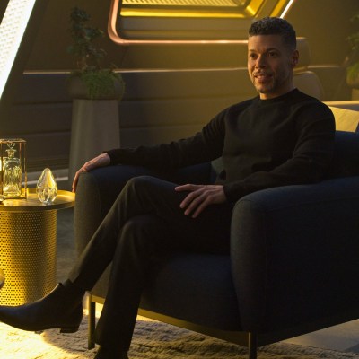 Wilson Cruz sits in a chair as Hugh Culber