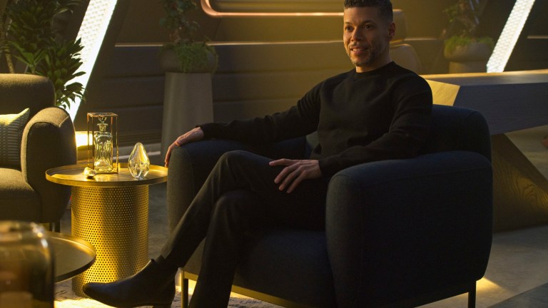 Wilson Cruz sits in a chair as Hugh Culber