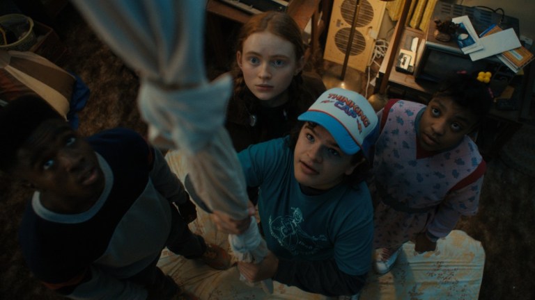 Lucas (Caleb McLaughlin), Max (Sadie Sink) Dustin (Gaten Matarazzo), and Erica (Priyah Ferguson) gather around a makeshift rope in Stranger Things season 4