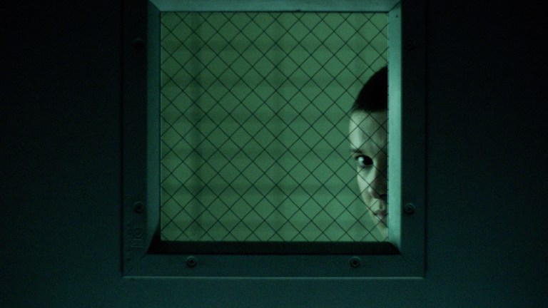 Eleven peeking through window in Stranger Things