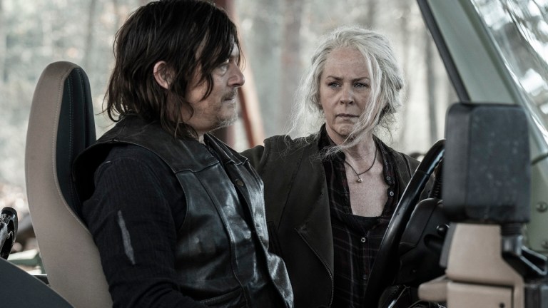 Norman Reedus as Daryl Dixon sits behind the wheel of a jeep while Melissa McBride as Carol looks on concerned.