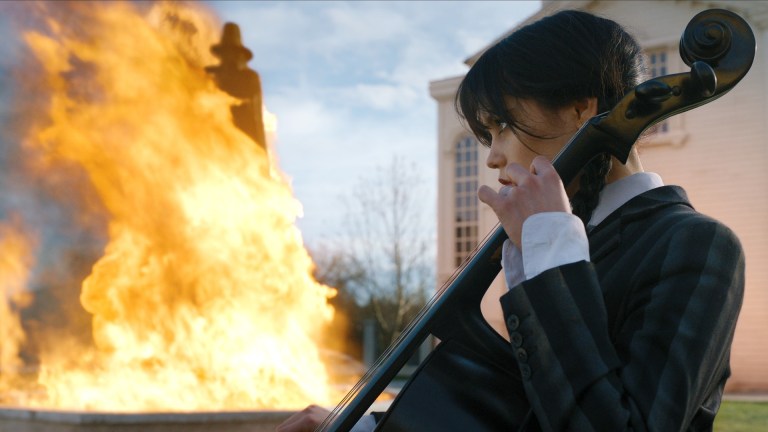Wednesday Addams (Jenna Ortega) plays Cello while a fire blazes in the background