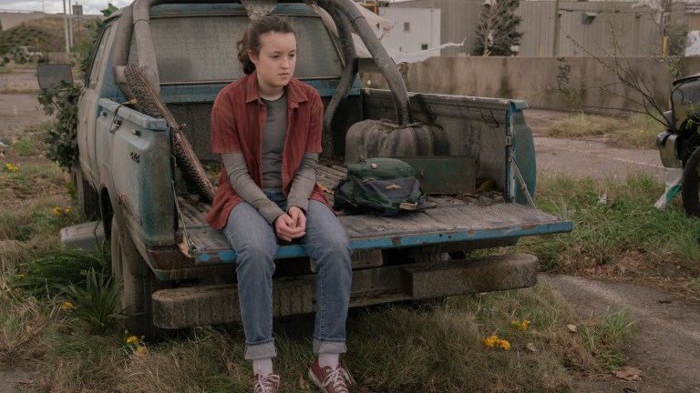 Ellie (Bella Ramsey) sits on the edge of an abandoned truck in The Last of Us