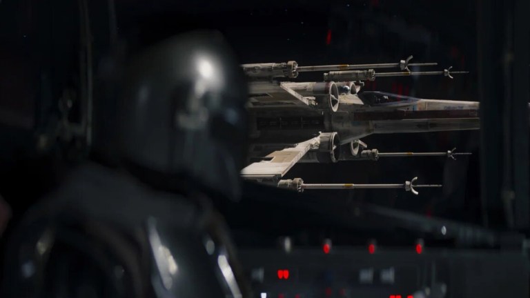 Din Djarin (Pedro Pascal) looks out the window of his ship and sees an X-Wing beside him