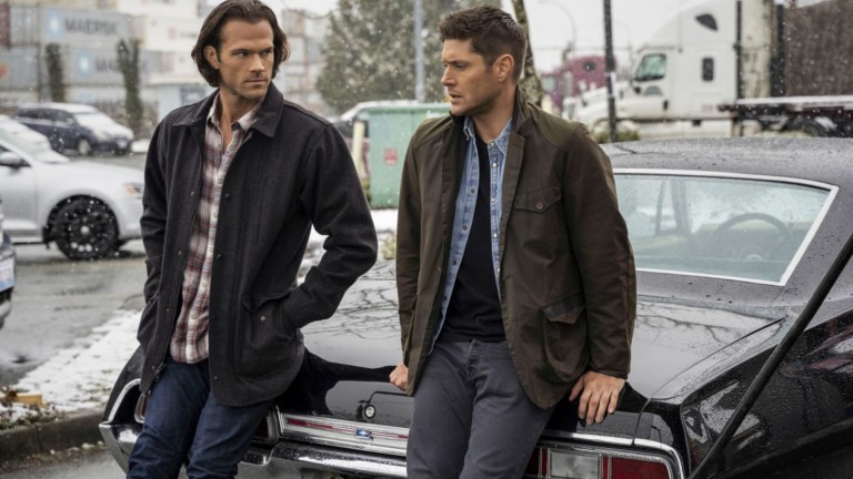 Dean and Sam Winchester lean on their iconic Chevy Impala on Supernatural