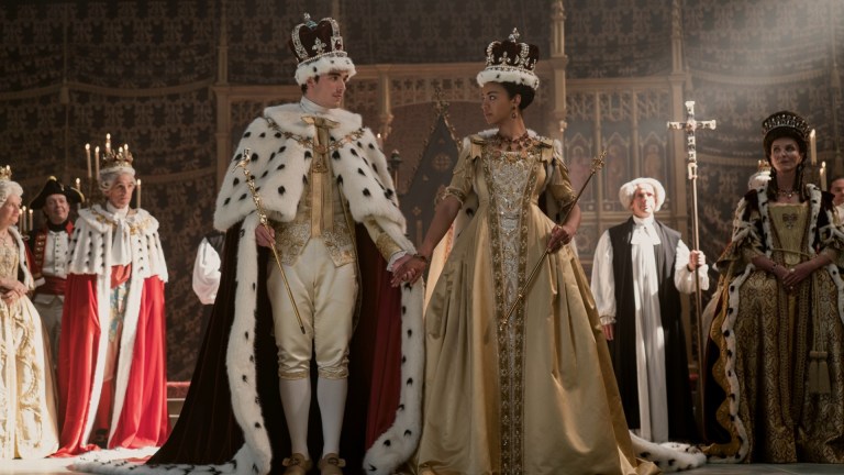 Corey Mylchreest as Young King George, India Amarteifio as Young Queen Charlotte, Michelle Fairley as Princess Augusta attend a royal coronation in episode 103 of Queen Charlotte: A Bridgerton Story