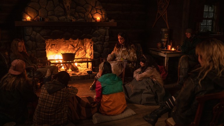 Liv Hewson as Teen Van, Courtney Eaton as Teen Lottie, Mya Lowe as Teen Gen and Sophie Nélisse as Teen Shauna sit around the cabin fireplace in YELLOWJACKETS, "Storytelling".