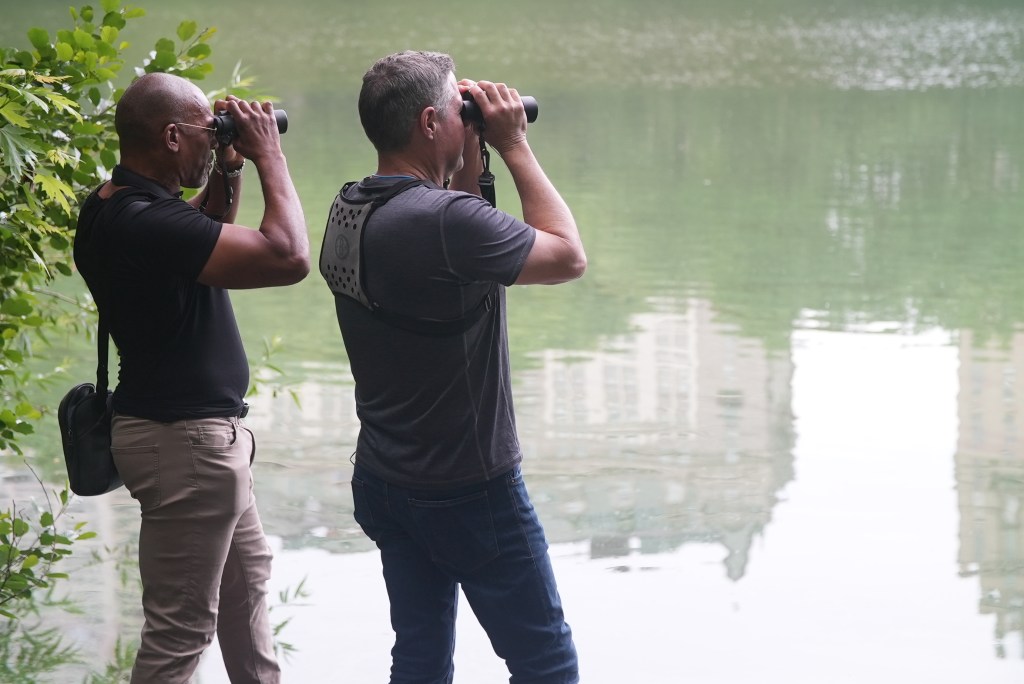 Christian Cooper and his friend, biologist and wildlife conservationist Jeff Corwin, look through binoculars across Central Park Lake. (National Geographic/Troy Christopher)