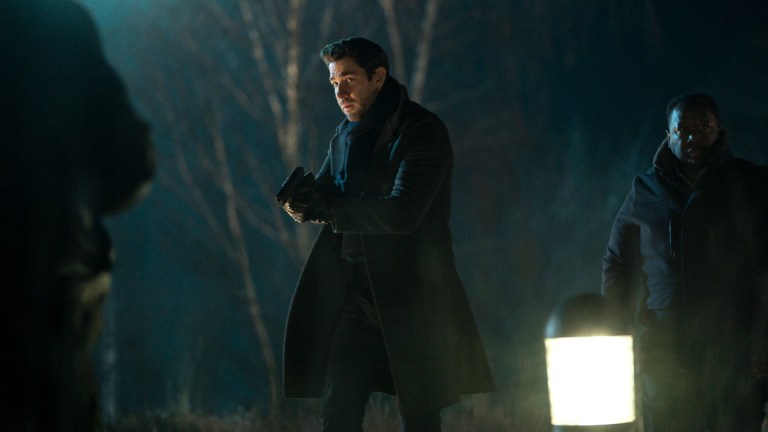 Jack Ryan (John Krasinski) walks armed through dark and ominous woods
