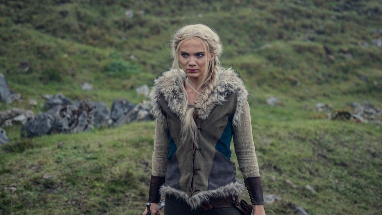 Ciri (Freya Allan) stands with a sword in the open countryside