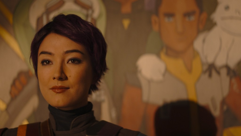 Sabine Wren (Natasha Liu Bordizzo) steht vor einem gemalten Wandgemälde der Ghost Crew aus Star Wars: Rebels