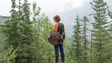 Percy Jackson (Walker Scobell) stands on a cliff overlooking Camp Half-Blood in Disney+'s Percy Jackson and the Olympians