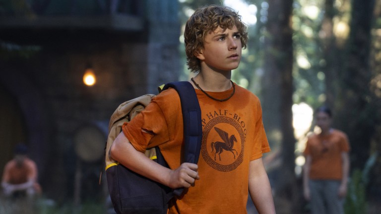 Percy Jackson (Walker Scobell) stands in an orange Camp Half-Blood t-shirt