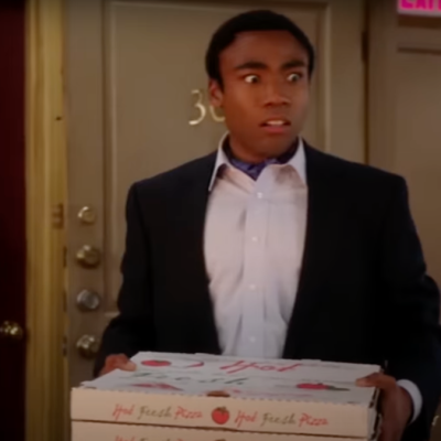 Troy Barnes (Donald Glover) holding a pizza with a horrified expression in Community "Remedial Chaos Theory."