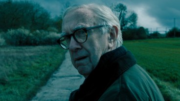 Jonathan Pryce as David Cartwright standing in a country lane in Slow Horses season 4