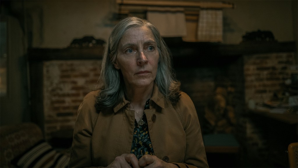 Standish from Slow Horses season 3 wearing a cardigan and sitting in a dark room