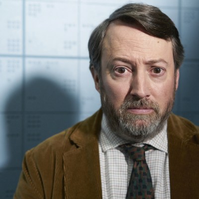 David Mitchell wearing a brown suit, white shirt and tie in BBC One series Ludwig