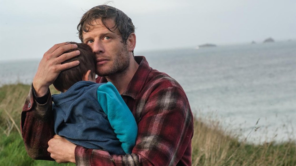 James Norton in a checked shirt holding a toddler at the Cornwall coastline for ITV&rsquo;s Playing Nice