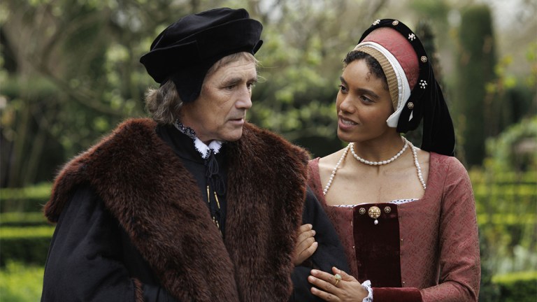 Mark Rylance and Maisie Richardson-Sellers in 16th century costume walking in a garden in Wolf Hall: The Mirror and the Light