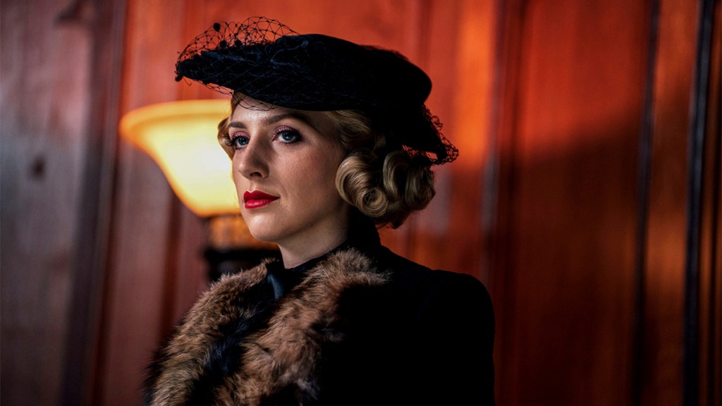 Ella Lily Hyland in a glamorous 1920s-style black hat and fur-lined coat