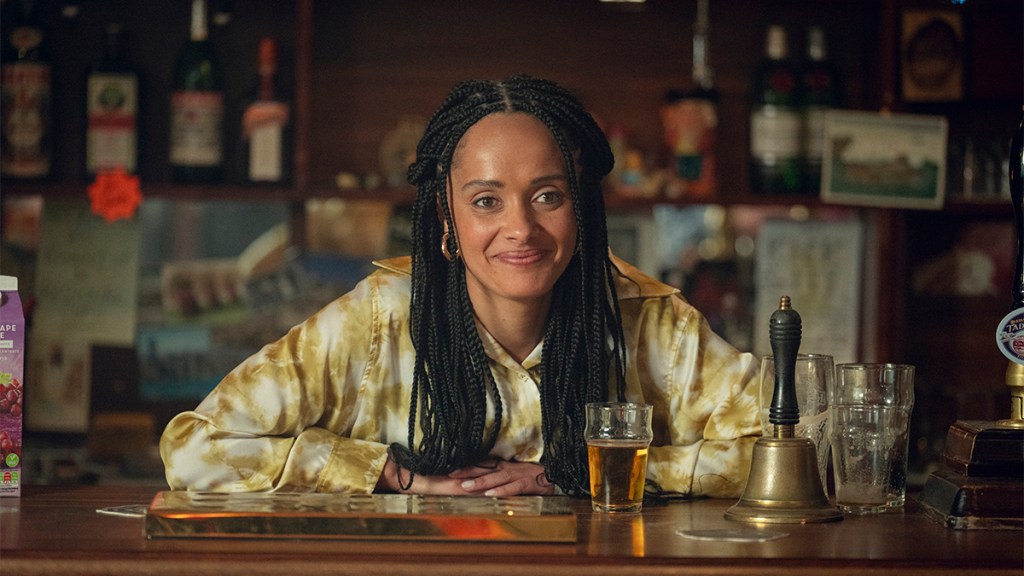 A woman with long braids behind the bar of a pub in Netflix&rsquo;s Toxic Town