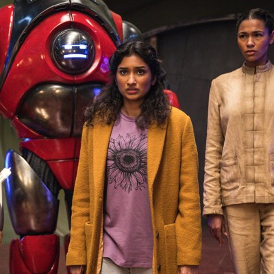 Eveyn Miller in beige dirty pyjamas, Varada Sethu in a yellow coat, and a red robot in Doctor who