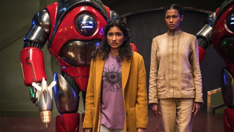 Eveyn Miller in beige dirty pyjamas, Varada Sethu in a yellow coat, and a red robot in Doctor who