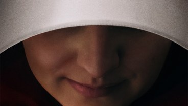 A close-up image of Elisabeth Moss smiling in a white bonnet