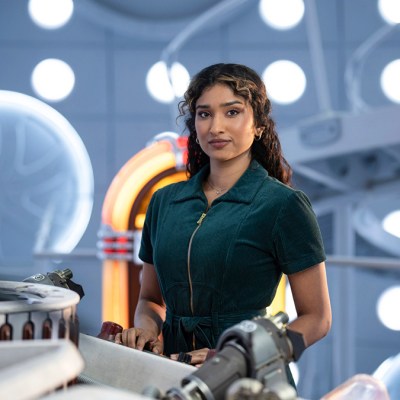 A woman in a green jumpsuit standing by the TARDIS console in Doctor Who