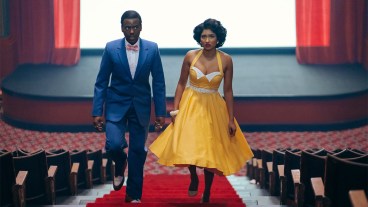 Ncuti Gatwa and Varada Sethu in 1950s clothing walking up the aisle of a cinema in Doctor Who episode Lux