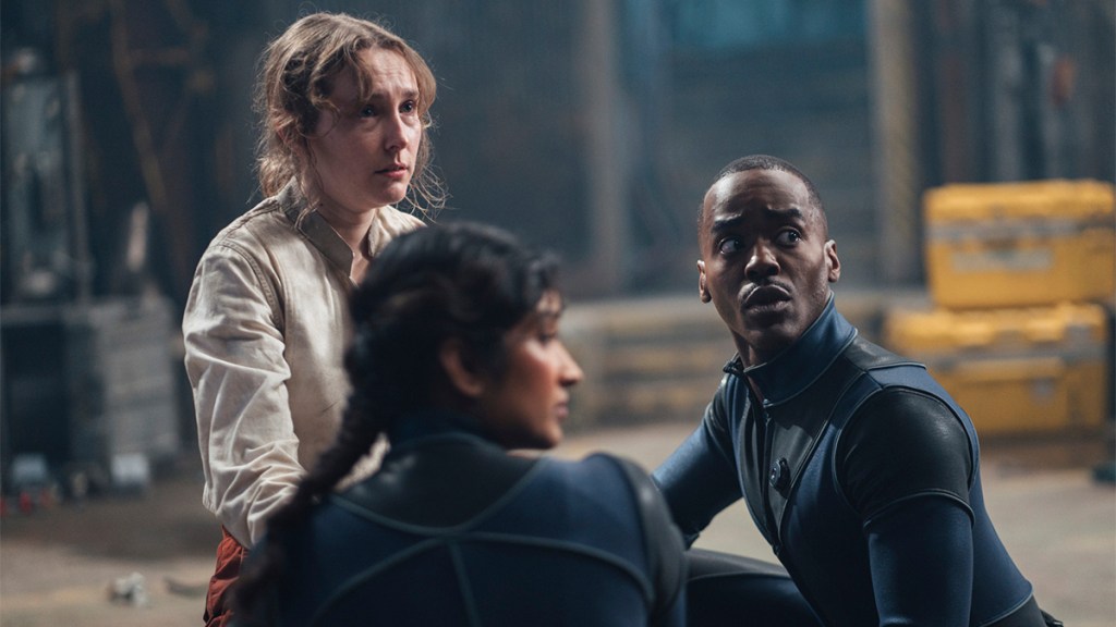 Ncuti Gatwa and Varada Sethu in tight-fitting blue spacesuits and Rose Ayling-Ellis wearing a beige jacket