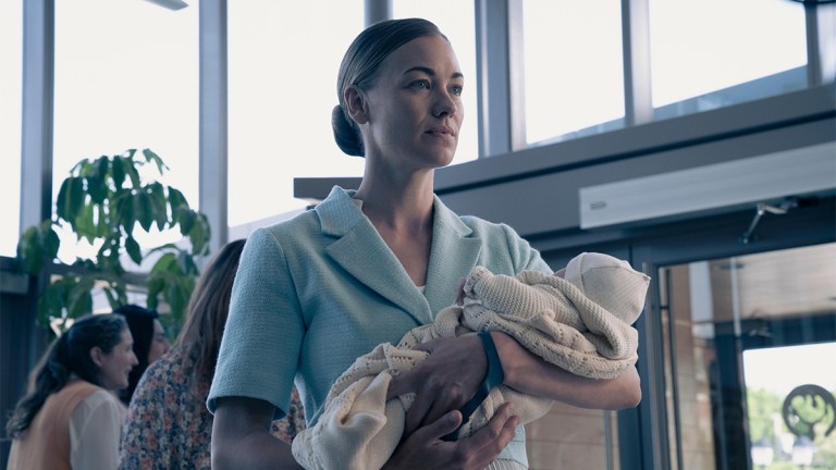 A blonde woman dressed in blue holding a baby