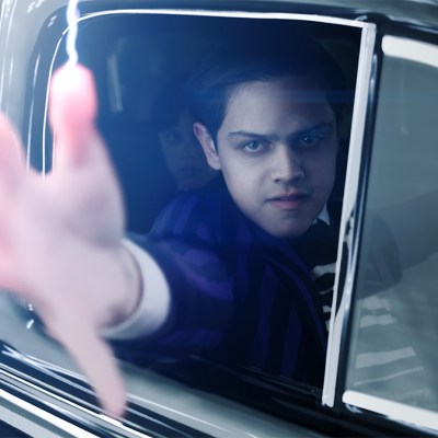Isaac Ordonez shooting electricity from his fingertips in a car as Pugsley Addams in the new Wednesday season 2 trailer