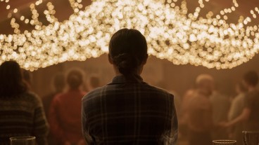 Ellie (Bella Ramsey) stands with her back to the camera at the Jackson NYE party in The Last of Us season 2.