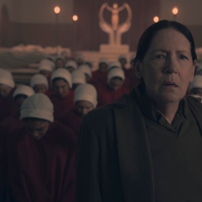 Ann Dowd looking serious backed by Handmaids and a Gilead statue in The Handmaid's Tale season six episode eight