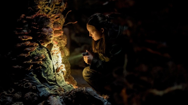 Ellie (Bella Ramsey) looks at an infected soldier breathing out spores in The Last of Us season 2