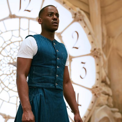 Ncuti Gatwa in a blue and white outfit standing in front of a clock in Doctor Who