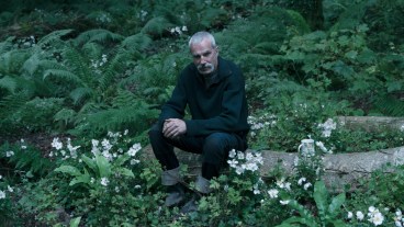 Daniel Day-Lewis sits on a log in the film Anemone.