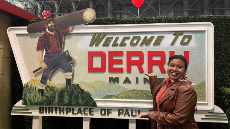 Den of Geek's Amanda-Rae Prescott poses in front of an It: Welcome to Derry sign at New York Comic Con 2025.