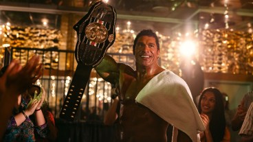 Dwayne Johnson holds up a championship belt in the movie The Smashing Machine