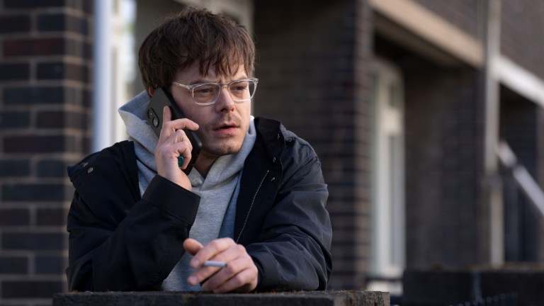 A journalist character played by Charlie Heaton smokes a cigarette and chats on his phone in Industry season 4 on HBO.