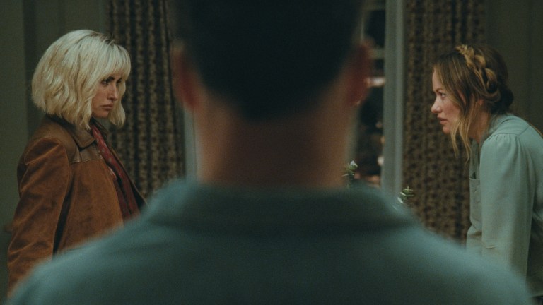 I’m not going to begin by stating emphatically that Penelope Cruz and Edward Norton play sexy-time ghosts in Olivia Wilde’s The Invite… but what if they might be ghosts, who happen to be sexy? I’m joking, but also stay with me for a minute. Still high off its buzzy premiere at Sundance, The Invite walks, blurs, and utterly dissolves all manner of boundaries and bougie festival taboos. Floating with an ethereal mystique that borders on the occult, as well as a painfully hilarious naturalism, this is a movie that orbits around a marriage in midlife catastrophe to the point of dizziness—an even more impressive feat after the film was marketed with such deceptive seduction. To be sure, Cruz and Norton are quite appealing, the seemingly perfect couple upstairs in a posh, if ancient, New York City tenement building. They initiate friendly conversation in the elevator, look gorgeous while making preternatural eye contact with neighbors, and apparently have passionate, earth-shattering sex after midnight each evening. Angela and Joe (Wilde and Seth Rogen) should know. They hear it every night through their ceiling, along with a 12-year-old daughter who is never seen in the film. There is something just otherworldly about Piña and Hawk (Cruz and Norton). And it leaves our central couple so alternatingly resentful and envious that the movie begins with an insert card of an Oscar Wilde quote: the eternal harbinger of doom for any romantic sentimentality beyond skin-deep nihilism. So when Joe and Angela invite Piña and Hawk over for a couple’s dinner, something aloof is in the air. Joe thinks it’s tension, as he is more than ready, eager even, to complain about the animal sounds through the floorboards. But for our spirited guests, the tension could have an entirely different flavor, one of suspense as they are here to—eventually—propose the downstairs stuffed shirts join them in a shared sexual experience. They want to swing by switching spouses for the night. The ghostly element I mentioned earlier is a bit of a come-on, but not by much. While the film quotes Wilde, Oscar, there’s more than a touch of Dickens and his descendants about the way Piña and Hawk float into our unhappy protagonists’ lives. They’re kinky Jacob Marleys, freaky Clarences, the angel of mercy in It’s a Wonderful Life who’s come to grant Jimmy Stewart a second chance at life after decades of disappointment by getting frisky in the kitchen. Even the audience is tempted into thinking they’re watching one kind of beguiling sex comedy, which we kind of get, even as we’re really being lured into a far more existential exploration of love and marriage after the romance has died. Are things not already in the Twilight Zone when an orgy invite from strangers amounts to the closest thing to high romance Joe or Angela’s heard in years? The trick of Olivia Wilde’s film and its inviting screenplay by Rashida Jones and Will McCormack is its structure. Based on the Spanish film The People Upstairs, Wilde’s picture borrows the original’s real-time setting of an unwieldy night of collapsing inhibitions and glasses of wine giving way to low-lit confessions in a cozy apartment’s corners. Among Jones and McCormack’s many scripted innovations, however, is the sensation that this is occurring in a bit of a theater workshop. This isn’t a knock at the performances, which are excellent, but at the sense we are sitting with a group of professionals, also over wine, as they psychoanalyze and deconstruct a messy, impermanent thing: the marriage of two people who care for each other but lost love a long time ago. Wilde shoots the film almost wholly in steadicam and in an underlit setting wherein the decorative paint colors and apartment accoutrements that Angela distracts herself with are indistinguishable. She isn’t wrong to note Joe is checked out when she talks about “finishing” the bedroom several years on, but Wilde the filmmaker cannot let her character hide behind minutiae. She drowns Angela and Joe’s faux domesticity into an inviting yet gloomy shadow world. Similarly, the helmer constantly films Rogen’s Joe as a domineering force in the life of his wife, towering over the frame and shot in harsh low light like a Halloween fright mask. At other times, the pair are caught in line of sight of each other in their horseshoe-shaped apartment, with the duo able to simply look up across the way and see one another in parallel windows. Yet they never do. It would make eye contact and break the spell of mutually agreed upon isolation. At its core, though, one does not cast a talent like Rogen, or for that matter Wilde at her most mischievous, and not revel in the humor. Rogen accentuates a new note of tired resignation to his likable, schlubby everyman persona, but there’s a lot more bitterness to Joe than Matt Remick in The Studio, as well as more pathos. This is a sad sack too self-involved to recognize he’s dragging his marriage down, but his unhappiness is not unsympathetic to anyone who reached a certain point in life where they realized they did not become the person they dreamed about when they were 20. It also makes his acerbic digs at Piña and Hawk, particularly for the latter’s clearly self-chosen name, all the more biting. Meanwhile Cruz delights in her role that purposefully walks a line between the ethereal and earthy. For much of the film, she might be a cipher, or certainly a projection of Joe and even Angela’s desires, albeit in very different contexts, but Cruz plays it with a rueful self-awareness. She’s the cat plucking at a pair of wounded canaries’ wings. The scene where she specifically attempts to uncoil Joe out of his wound-up funk to Sade’s now 26-year-old(!) “By Your Side” is a harmonious car crash; a collision of sweetness and cringe, reverie and gallows humor despair. And I haven’t even mentioned his “dance” moves. The Invite is a shimmering dramedy for adults of a certain age, and perhaps a sobering epiphany that this can now be so acutely tailored to elder Millennials and younger Gen-Xers at that. The film is genuinely sexy but in the awkward and disarming way of clumsy foreplay. It stumbles and stammers, with its proverbial pants caught around the ankles before the whole thing tonally keels over. Yet for all the screenplay’s verbose intellectualization about sensuality, and Wilde’s obvious preoccupation with it as a storyteller, the main event is something more intimate and unspoken. It’s a lament about the passage of time, milestones left discarded, and maybe even marriages that also have outlived their shelflife. One might even call it haunting, complete with the mysterious good-looking specters descending from above. Penelope Cruz and Olivia Wilde in The Invite Review