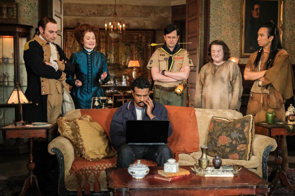"Across the Pond" - Coverage of the CBS Original Series GHOSTS, scheduled to air Thursday, May 21 (9:30-10:00 PM, ET/PT) on the CBS Television Network.   Pictured L to R: Brandon Scott Jones as Isaac, Rebecca Wisocky as Hetty, Utkarsh Ambudkar as Jay, Richie Moriarty as Pete, Betsy Sodaro as Nancy and Román Zaragoza as Sasappis.  Photo: Bertrand Calmeau/CBS ©2026 CBS Broadcasting, Inc. All Rights Reserved.